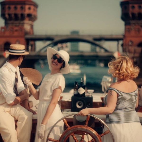 Gäste im twenties Style auf der Motoryacht Fitzgerald mit der Oberbaumbrücke im Hintergrund